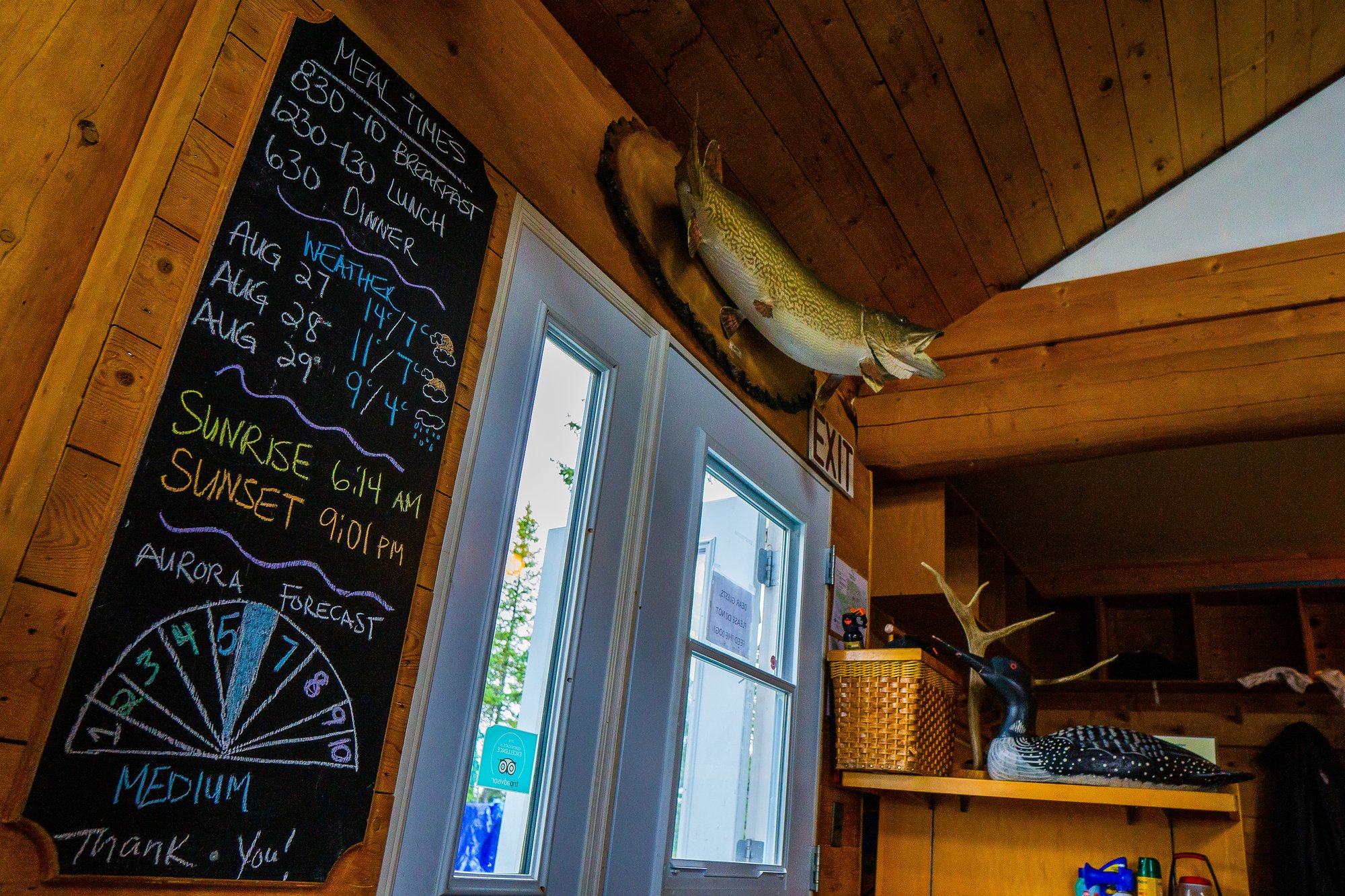 A chalk board sign displays daily activities and dinning times for the lodge. It is hung by the main entrance to the lodge.